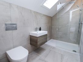 A bathroom with a toilet, vanity, and shower at Bigting in Rhosneigr