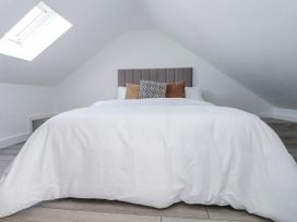 A bedroom with a bed and cushions at Bigting in Rhosneigr