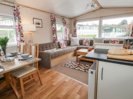 A living room with a sofa and dining area at Swanage Coastal Park Caravan in Swanage