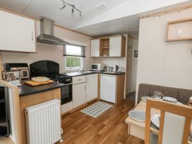 A kitchen with appliances and dining set at Swanage Coastal Park Caravan in Swanage