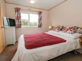 A bedroom with a bed and television at Swanage Coastal Park Caravan in Swanage