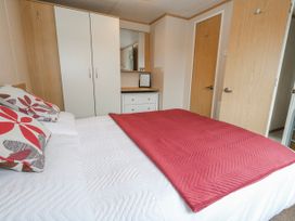 A bedroom with a bed and wardrobe at Swanage Coastal Park Caravan in Swanage