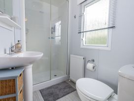 A bathroom with a shower, toilet, and sink at Swanage Coastal Park Caravan in Swanage