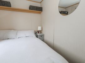 A bedroom with a bed and a nightstand at Swanage Coastal Park Caravan in Swanage