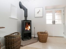 A living room with a wood burning stove and baskets at Velindra Farm Cottage Hereford