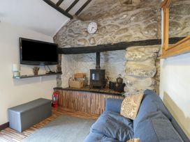A living room with a fireplace and television at Fullers Studio in Caergeiliog