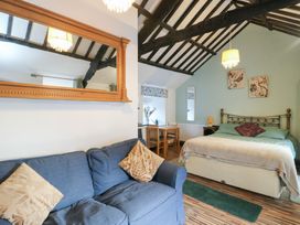 A bedroom with a bed, sofa and dining table at Fullers Studio, Caergeiliog