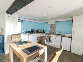 A kitchen with a table and chairs, appliances and cabinetry at The Mill in Holyhead