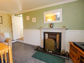 A living room with a fireplace and dining table at Ty Crigyll in Caergeiliog