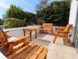 A wooden patio with chairs and a table at Ty Crigyll in Caergeiliog