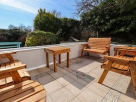 An outdoor seating area with wooden chairs and a small table at Ty Crigyll in Caergeiliog