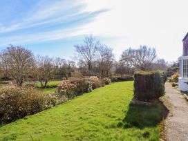 A garden with grass, trees, and a pathway at Ty Crigyll in Caergeiliog