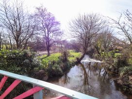 A view of a river surrounded by grass and trees at Ty Crigyll in Caergeiliog