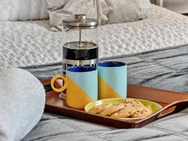 A tray with mugs, French press, cookies, and towel in a bedroom at Windsor House in York