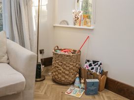 A living room corner with a basket of toys and children's books at North Cottage in Bowness-On-Windermere