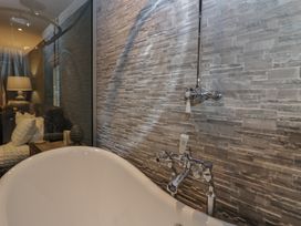 A bathroom featuring a bathtub and stone wall at North Cottage Bowness-On-Windermere