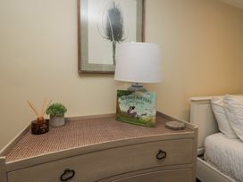 A dresser with a lamp, book, and decorative items at North Cottage Bowness-On-Windermere