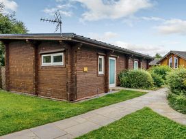 A wooden cabin with a pathway and greenery at Chestnut Spa in Carlton Miniott near Thirsk