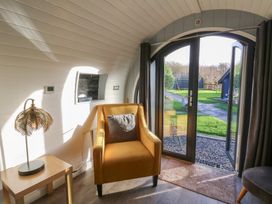 A living room with an armchair and a door leading to the outdoor area at Garden Lodge 5 Swansea