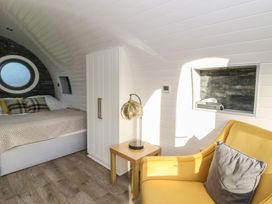 A bedroom with a bed, nightstand, and armchair at Garden Lodge 5 in Swansea