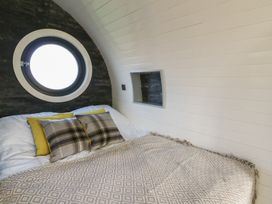 A bedroom with a bed and round window at Garden Lodge 5 Swansea