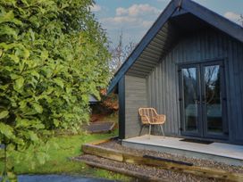 A cabin with a chair and a door at Garden Lodge 7 Swansea