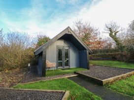 A cabin with a chair and pathway at Garden Lodge 7 in Swansea