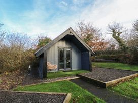 A cabin with a chair and pathway at Garden Lodge 8 in Swansea