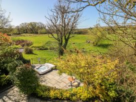 An outdoor area with a hot tub and a table with chairs at Rose Apartment Old Walls, Llanrhidian, Gower