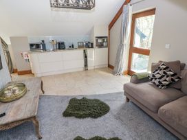 A living room with a kitchen area and sofa at Rose Apartment in Old Walls, Llanrhidian, Gower