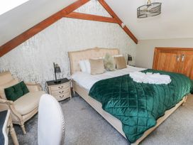 A bedroom with a bed and armchair at Rose Apartment in Old Walls, Llanrhidian, Gower
