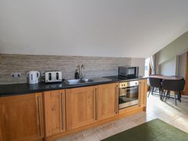 A kitchen with wooden cabinets and appliances at Willow Apartment in Swansea