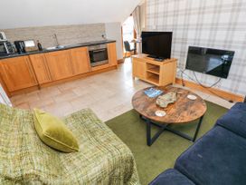 A living room with a kitchen area and a coffee table at Willow Apartment in Oldwalls, Llanrhidian, Gower
