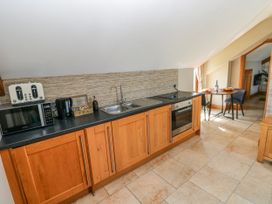 A kitchen with appliances and a dining area at Willow Apartment in Oldwalls, Llanrhidian, Gower