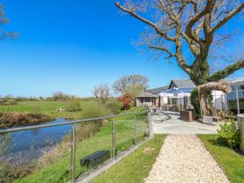 An outdoor area with a tree, water, and patio furniture at Willow Apartment in Oldwalls, Llanrhidian, Gower