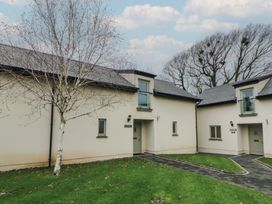 Two buildings with grass and a pathway at Ivy Cottage in Swansea