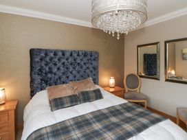 A bedroom with a bed, bedside tables, and a chair at Ivy Cottage in Swansea