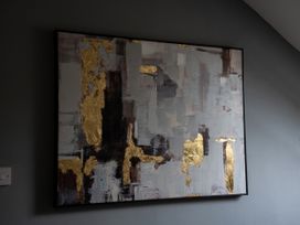 An abstract artwork with gold accents on a wall at Ivy Cottage Oldwalls near Reynoldston