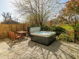 A garden with a hot tub and wooden furniture at Ivy Cottage Oldwalls, Llanrhidian, Gower