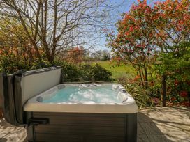 A hot tub on a patio surrounded by plants at Ivy Cottage Oldwalls, Llanrhidian, Gower