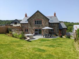 A house with patio furniture and a hot tub at Knowle House Okehampton