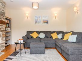 A living room with a sectional sofa and bookshelf at Knowle House in Okehampton