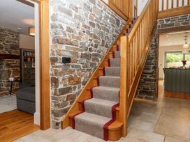 A staircase with a stone wall in a hallway at Knowle House in Okehampton