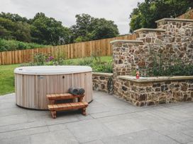 A garden with a hot tub and stone wall at Knowle House in Okehampton