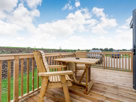 A deck with a table and chair at Pear Tree Spa (Pet) Carlton Miniott near Thirsk