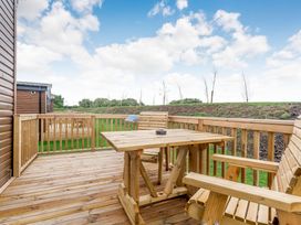 An outdoor patio with a wooden table and chairs at Pear Tree (Pet) Carlton Miniott near Thirsk