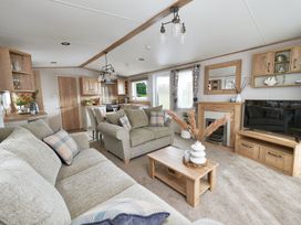 A living room with a sofa and television at Juniper Waterside Spa in Carlton Miniott near Thirsk