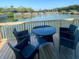 An outdoor terrace with a table and chairs at Acacia Waterside Spa, Carlton Miniott near Thirsk