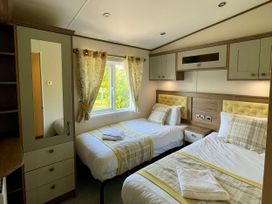 A bedroom with two beds and a window at Acacia Waterside Spa Carlton Miniott near Thirsk