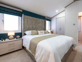 A bedroom with a bed and bedside table at Rowan Waterside Spa Carlton Miniott near Thirsk